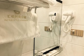 Un baño con una toalla colgada en un perchero, un secador de pelo y un teléfono en la pared.