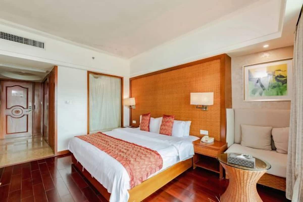 A hotel room with a large bed, a sitting area with a sofa, a small table, and a painting on the wall.