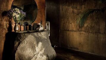 Experience a minimalist bathroom retreat with a large mirror, stone sink, and decorative vase.