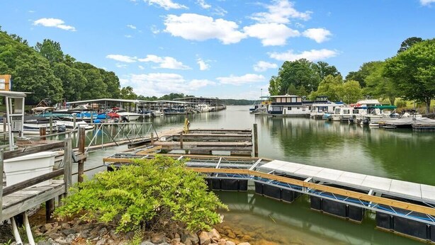 A marina with docked boats, wooden walkways, and a calm lake surrounded by trees.