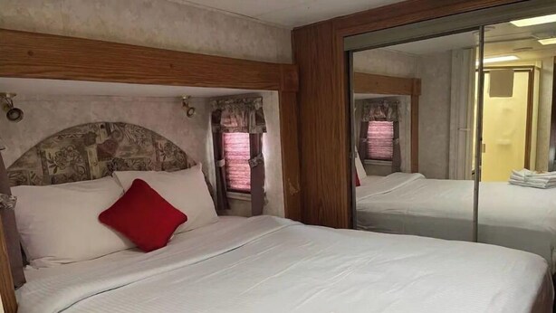 Ein Hotelzimmer mit einem großen Bett, einem Holzkopfende, einem Spiegel und einem kleinen Tisch mit Toilettenartikeln.