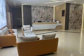 A hotel lobby with a reception desk, seating area, and a marble wall. - Hongye Hotel (Langxi)