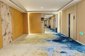 A hotel corridor with a blue carpet, beige walls, and doors leading to rooms. - Hongye Hotel (Langxi)