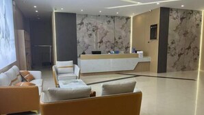 A modern hotel lobby with a reception desk, seating area, and marble walls. - Hongye Hotel (Langxi)