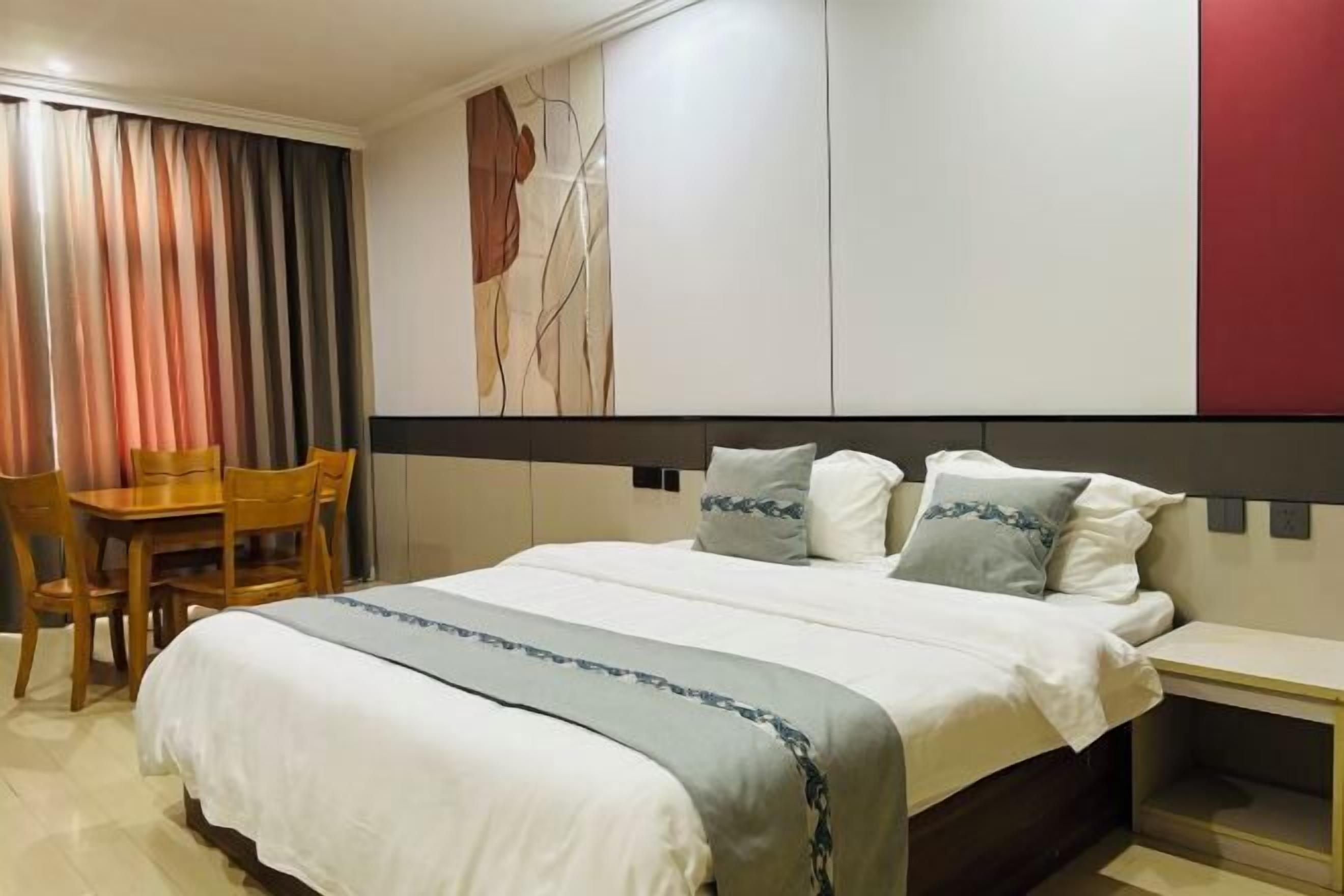 A hotel room with a bed, bedside table, and a desk with chairs.