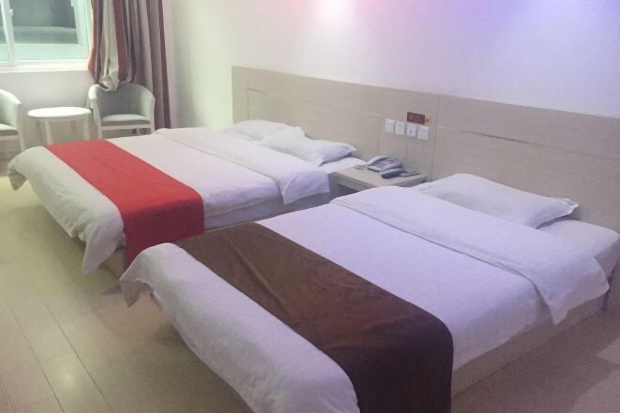 Habitación de hotel con dos camas, una mesita y una silla.