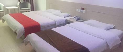Habitación de hotel con dos camas, una mesita y una silla.