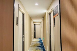 Pasillo de hotel con puertas a ambos lados, suelo alfombrado y un letrero que indica la disponibilidad de habitaciones.