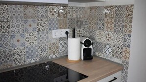 Une cuisine avec un plan de travail noir, un appareil électroménager blanc et un pare-feu décoré.
