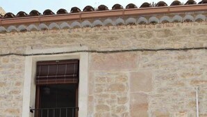 Un bâtiment en pierre avec une porte en bois et une fenêtre dotée d’une grille en métal.