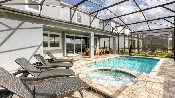 A covered outdoor swimming pool with lounge chairs, a hot tub, and a patio area. - Huge 9BR Vacation Villa in Orlando | Near Disney (Kissimmee)