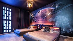 A bedroom with two beds, a mural of space-themed artwork, a unique light fixture, and a modern design. - Huge 9BR Vacation Villa in Orlando | Near Disney (Kissimmee)