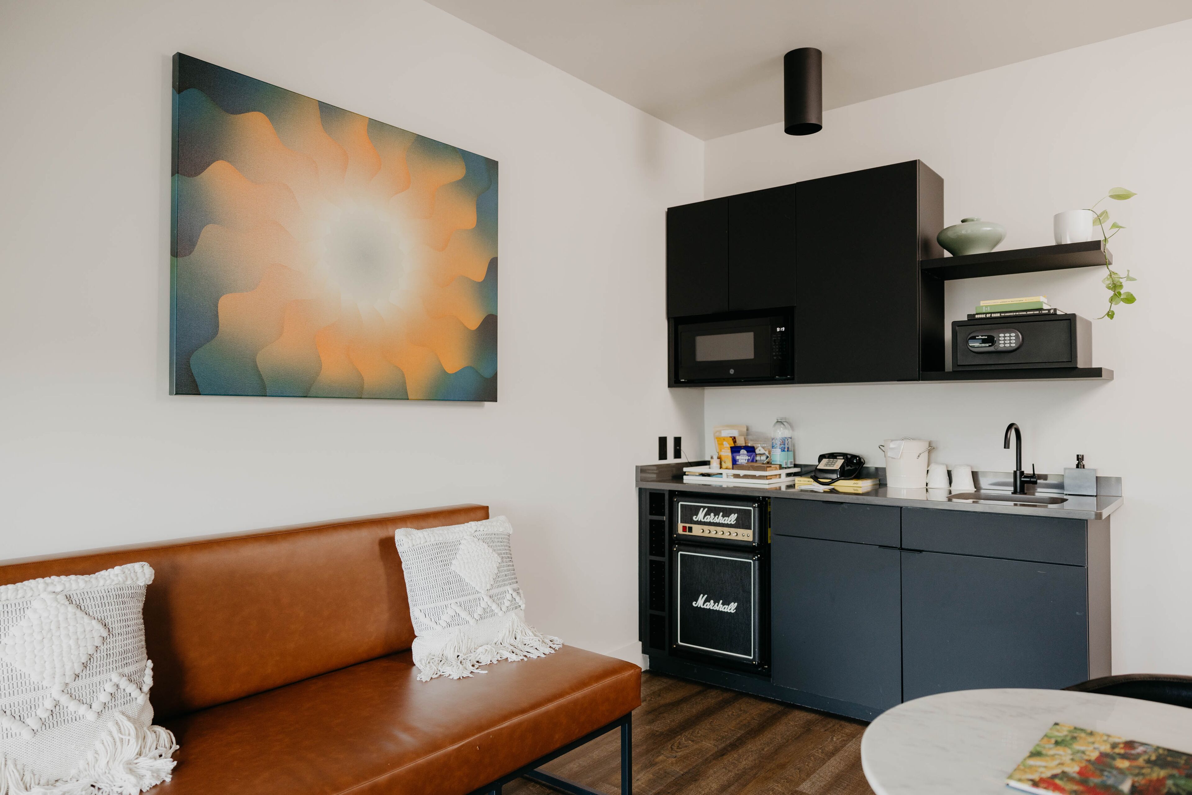 A modern kitchen with a microwave, coffee maker, and a small shelf with books and a plant.