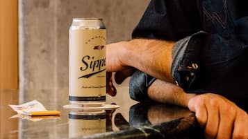 A person sitting at a table with a can of Sippin' Gold beer and a menu.