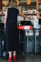 A bar area with a check-in counter, a marble wall, and a variety of bottles on shelves.