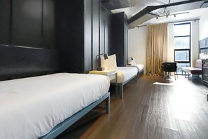 Une chambre d’hôtel moderne équipée de deux lits, d’un bureau, d’une chaise et d’une grande fenêtre avec des rideaux.