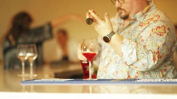 Una persona vertiendo un líquido rojo en un vaso en un bar.