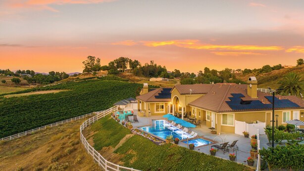 A large house with a swimming pool, surrounded by a white fence and lush greenery. - Gaia Inn and Spa - Adults Only - Temecula Wine Country (Temecula)