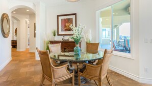 A dining area with a glass table surrounded by wicker chairs, a vase with flowers, and a framed picture on the wall. - Gaia Inn and Spa - Adults Only - Temecula Wine Country (Temecula)