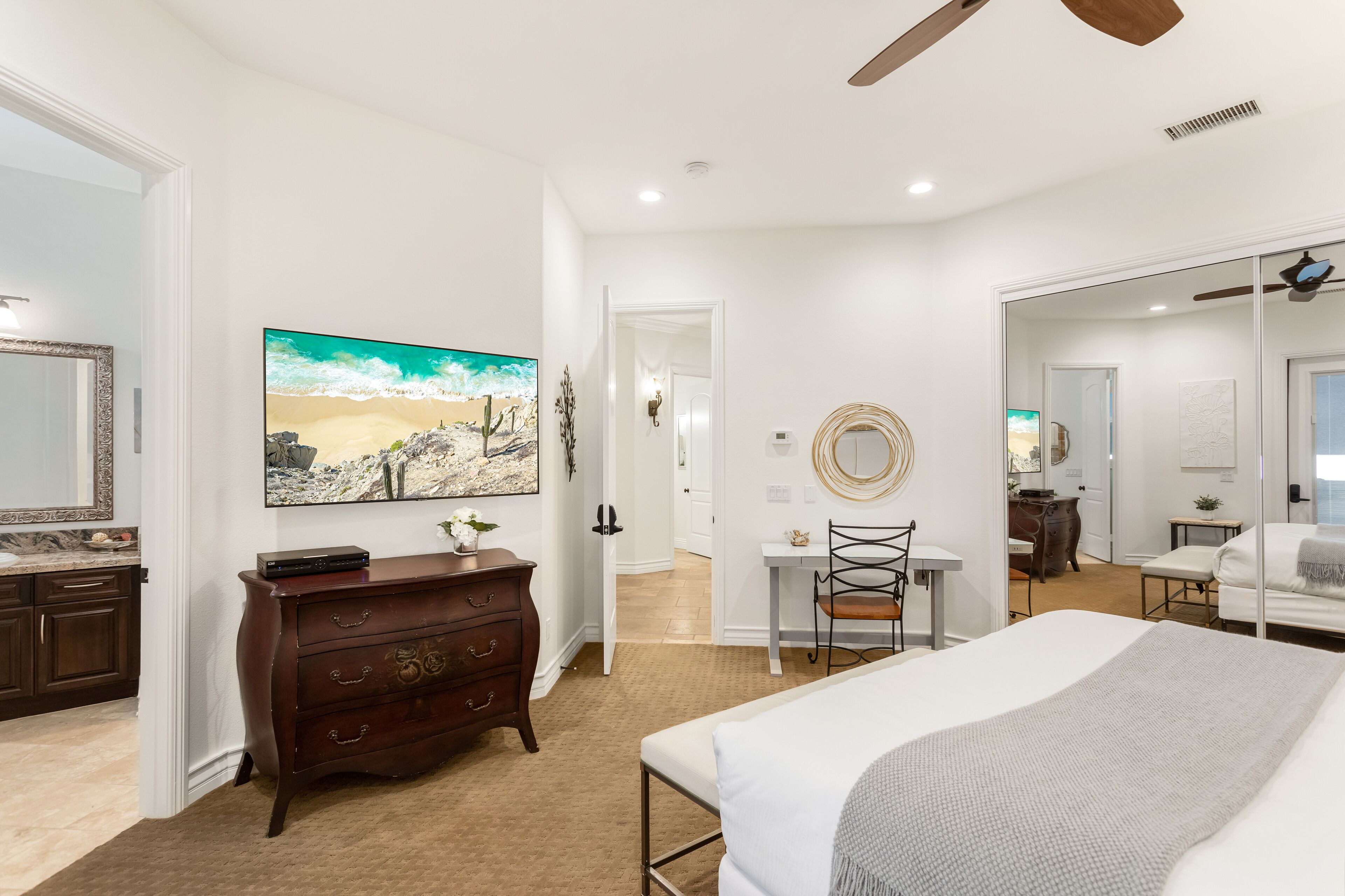 A bedroom with a bed, dresser, and a painting of a desert landscape.