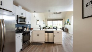 Une cuisine moderne dotée d’appareils électroménagers en acier inoxydable, d’un îlot central et d’un ventilateur de plafond.