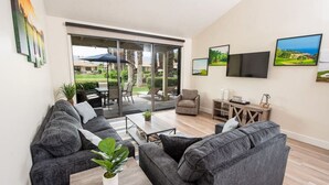 Un salon moderne avec des canapés gris, une table basse et un téléviseur fixé au mur.