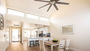 Une cuisine spacieuse dotée d’un îlot central, de planchers en bois et d’un ventilateur de plafond.