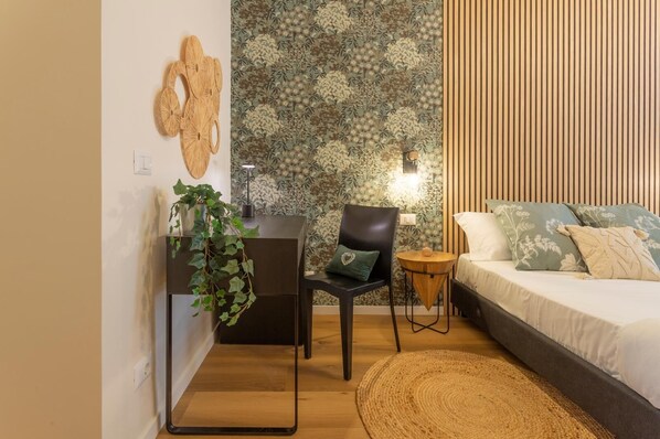 Une chambre avec un lit, un bureau et une chaise, une petite table ronde et une plante.