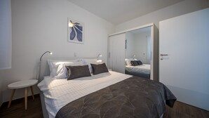 A bedroom with a bed, bedside table, and a mirror on the wall.