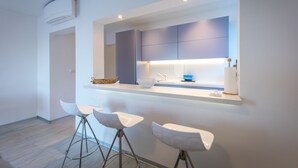 A modern kitchen with a built-in island, bar stools, and a large window.