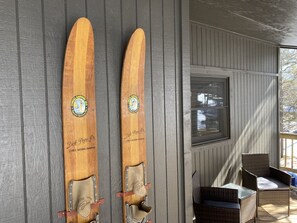 Deux paires de skis en bois, fixées au mur, avec un logo et une inscription, une fenêtre et des meubles en osier.