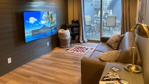 Ett modernt vardagsrum med en platt-TV, en soffa, ett soffbord och ett schackbräde.