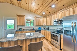 Enjoy cooking in this well-equipped kitchen with a large island, stainless steel appliances, and a window offering a view of the surrounding landscape.