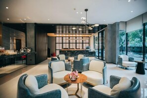 A modern interior with seating, a kitchen area, and large windows. - Guang Ao Hotel (Haikou)