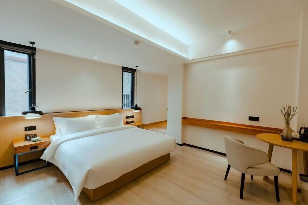 A modern hotel room with a large bed, bedside tables, a desk, and a chair.