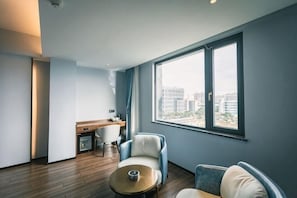 A modern hotel room with a large window, a desk, a chair, and a sofa. - Guang Ao Hotel (Haikou)