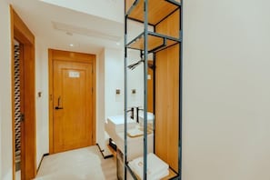 A compact hotel room with a wooden door, a bed, a metal wardrobe, and a small bathroom. - Guang Ao Hotel (Haikou)