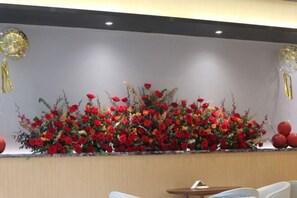 A reception area with a large floral arrangement, a reception desk, and a seating area. - Guang Ao Hotel (Haikou)