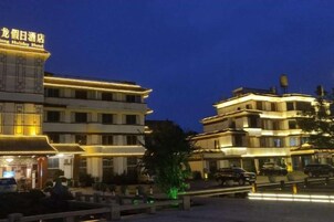 A multi-story hotel with illuminated signage, a courtyard with seating, and a street view.