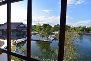 Um edifício tradicional com um lago e árvores em primeiro plano.