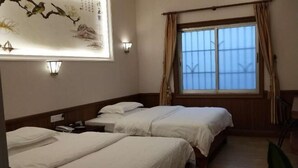 A hotel room with two beds, a window with curtains, wall-mounted lights, and a decorative wall piece. - Feilong Holiday Hotel (Xinxing)