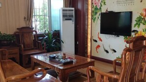 A traditional room with wooden furniture, a television, and a decorative wall. - Feilong Holiday Hotel (Xinxing)