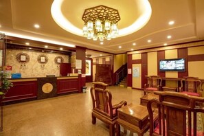 A hotel lobby with a reception desk, seating area, and a staircase. - Feilong Holiday Hotel (Xinxing)
