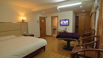 Una habitación de hotel con cama, televisión, escritorio y silla.