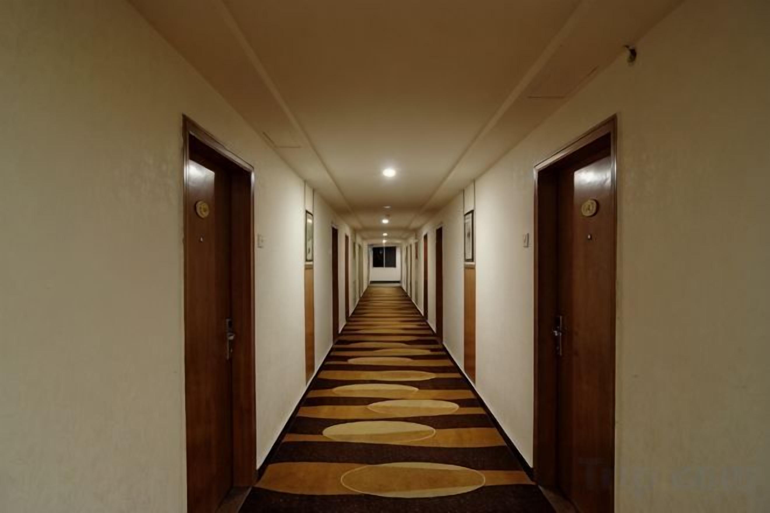 A hotel hallway with doors on both sides, a carpeted floor, and a long corridor.