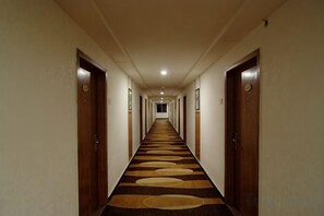 Un pasillo de hotel con puertas a ambos lados, piso alfombrado y una larga extensión.