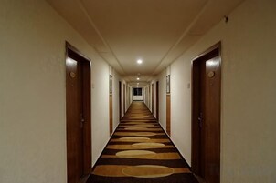 Un pasillo de hotel con puertas a ambos lados, piso alfombrado y una larga extensión.