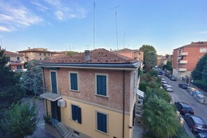 A two-story building with a tiled roof, multiple windows with shutters, and a small balcony. - UR-NEST Mitelli, a bedroom (Bologna)