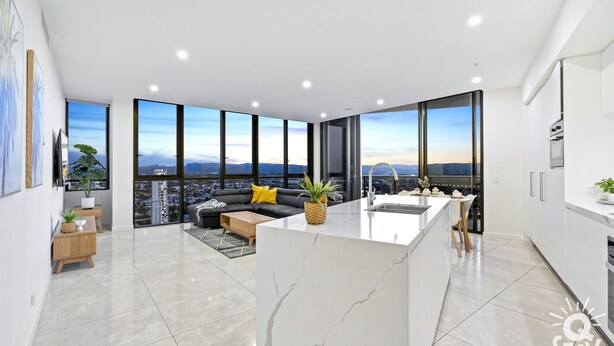 A modern apartment with a large kitchen, dining area, and a balcony with a city view. - Ruby Apartments - Q Stay (Surfers Paradise)