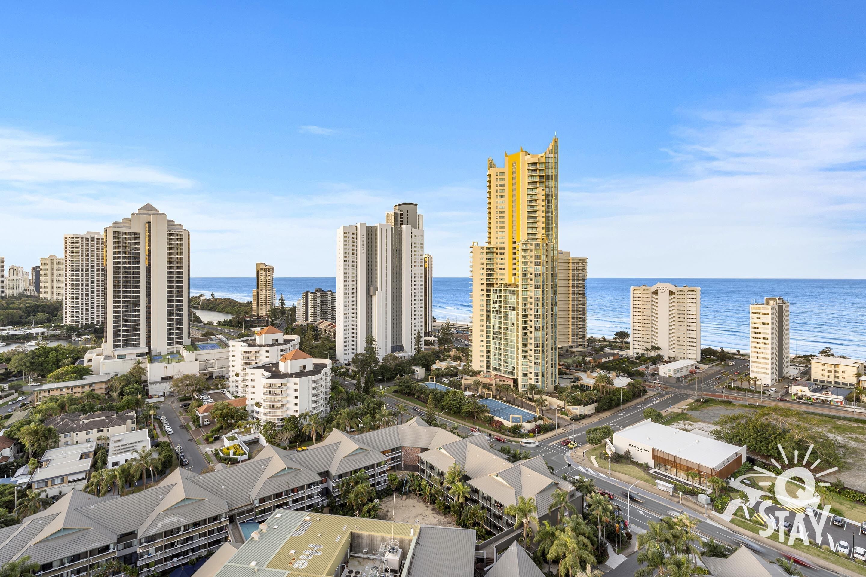 Eine Küstenstadt mit Hochhäusern, blauem Himmel und einem Strand im Hintergrund.